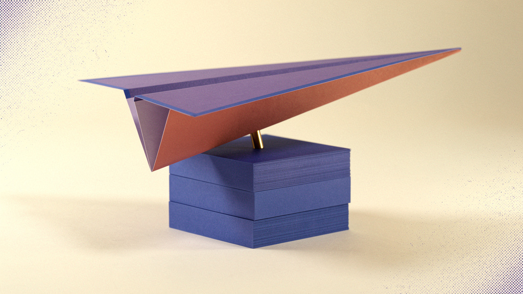 A folded lavender paper wing rests above cobalt paper blocks and a small brass support.